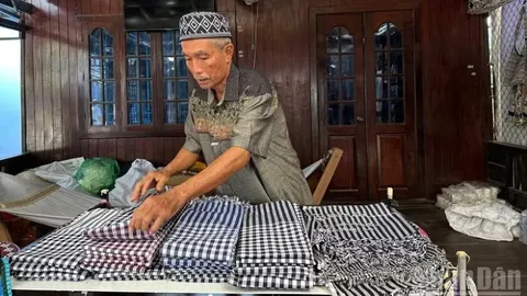 Ông Mohamad chăm chút sản phẩm dệt thổ cẩm Chăm trưng bày tại cửa hàng